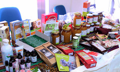 Mesa con productos de comercio justo: paquetes, tarros y bolsas de alimentación y jabones.
