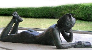 Estatua de bronce de la Biblioteca General, de mujer desnuda leyendo un libro tendida boca abajo