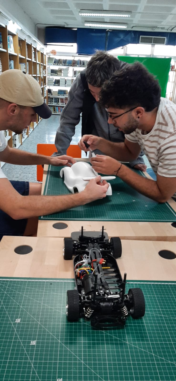 Tres estudiantes preparan un prototipo de automóvil en una biblioteca