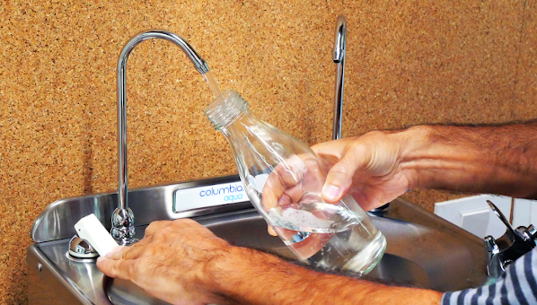 "Fuente de agua. Unas manos sostienen una botella mientras se llena de agua"