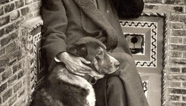 Foto de Pérez Galdós sentado en un banco de obra en un rincón, con una mano sobre un perro.