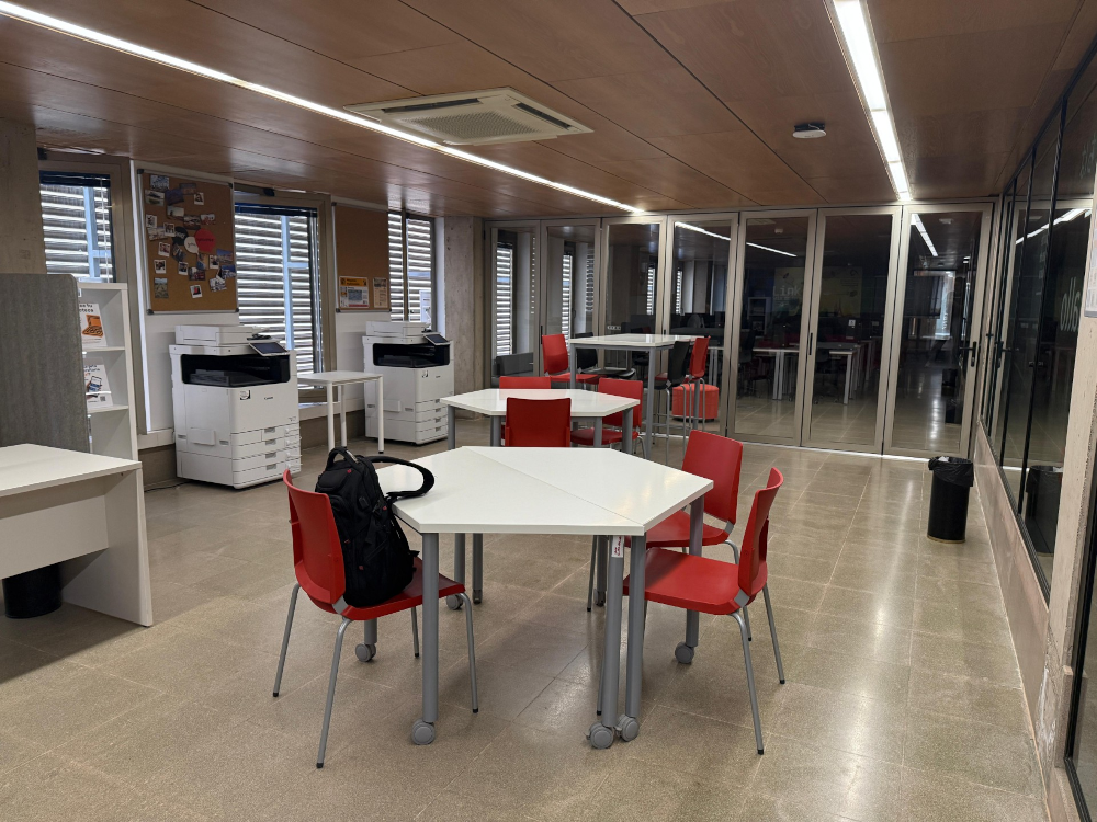 Fotocopiadoras y mesas y sillas en una sala de biblioteca