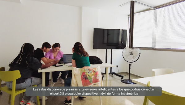 4 alumnas estudian ante una mesa junto a un televisor en una sala de estudio.