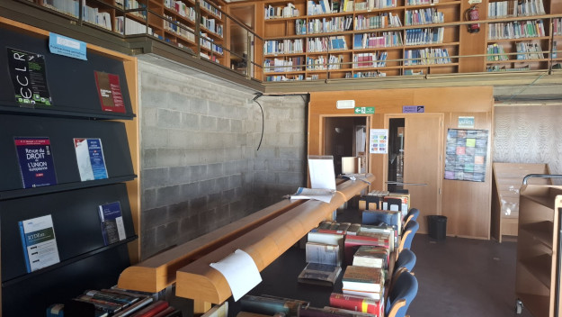 Sala de biblioteca con dos plantas con parte en obras, con bloque a la vista.