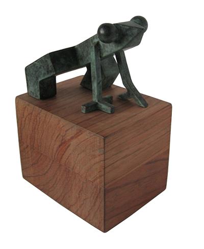 Vista de una pequeña escultura de una rana estilizada sobre un taco de madera. Diseño de Pablo Amargo