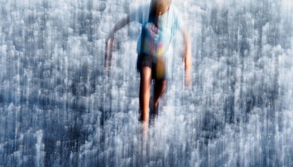 Fotografía artística de un adolescente en torno a una superficie lluviosa
