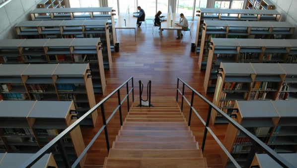 Imagen de interior de la Biblioteca de Veterinaria con escaleras, mesas con alumnado sentado y vistas al exterior