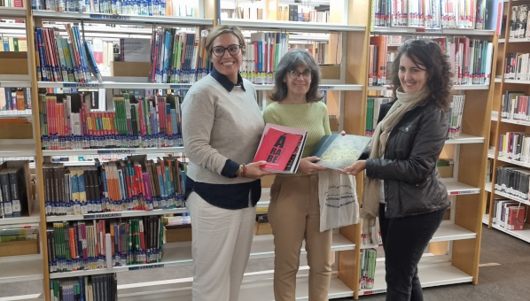 Foto de grupo de tres mujeres mostrando libros frente a estantes de biblioteca: de izquierda a derecha: Cristina Alfonzo de Tovar, coordinadora del CRAAL, Ana Ruth Vidal Luengo, responsable del área de árabe del CraaL, y Teresa Cabrera Morales, de la Biblioteca Universitaria