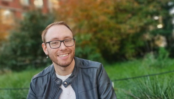 Chico posa sonriente con jardín al fondo