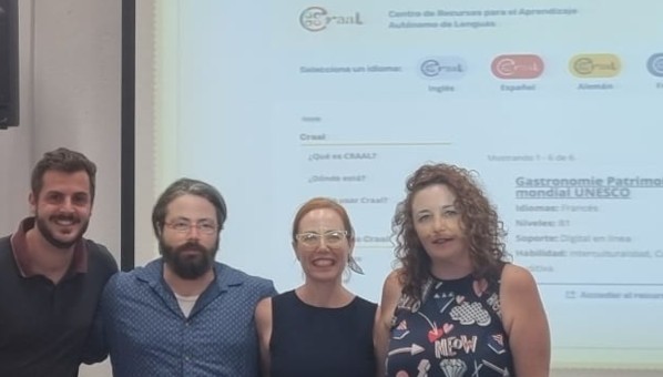 4 docentes; dos profesores y dos profesoras, posan sonrientes frente a pantalla en la que se proyecta un recurso de francés en el portal craal.