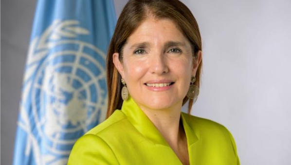 Mujer posa con bandera de la ONU detrás.